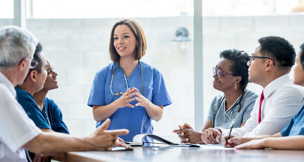 A nurse addresses a conference room of doctors and administrators